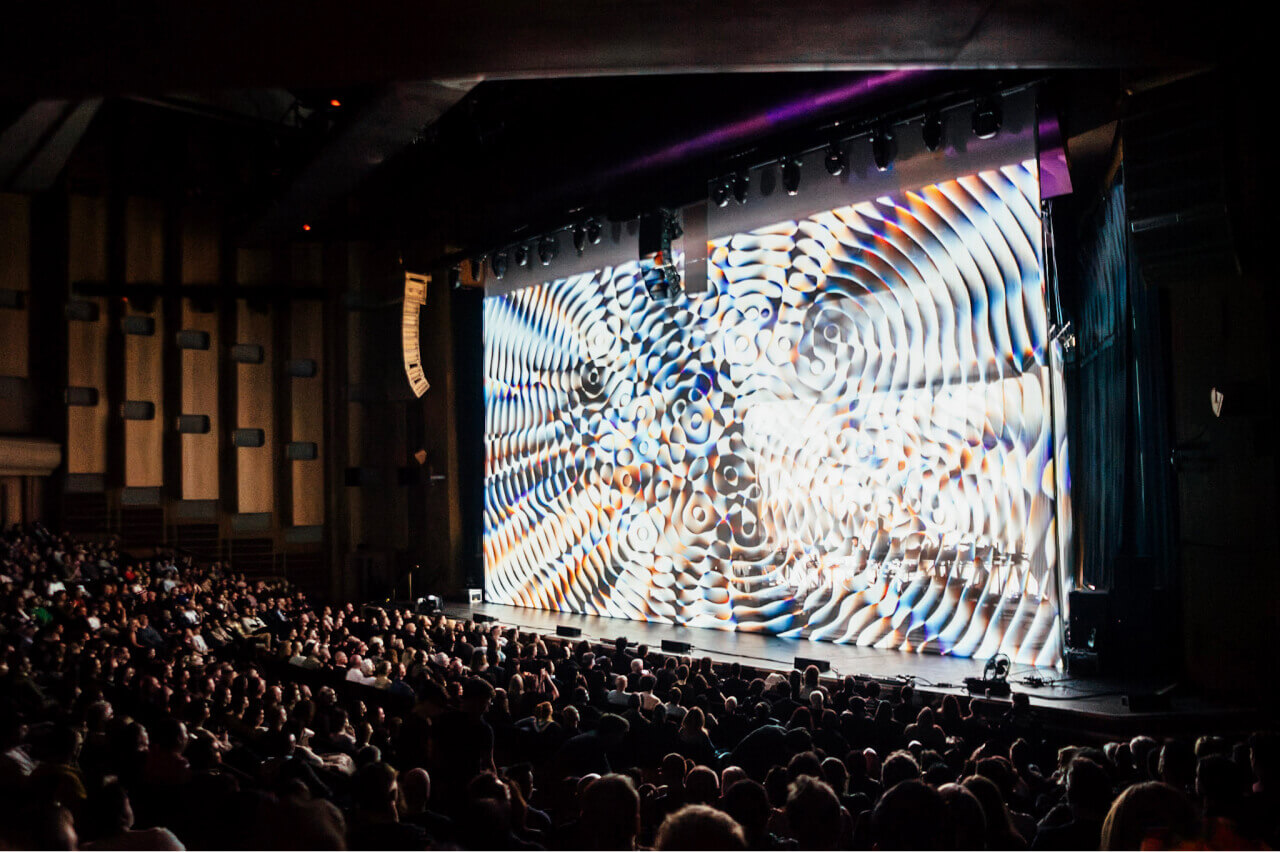 Audience contemplating the 'Cardano Circles' animation during Max Cooper's performance at Barbican Centre Hall in London.