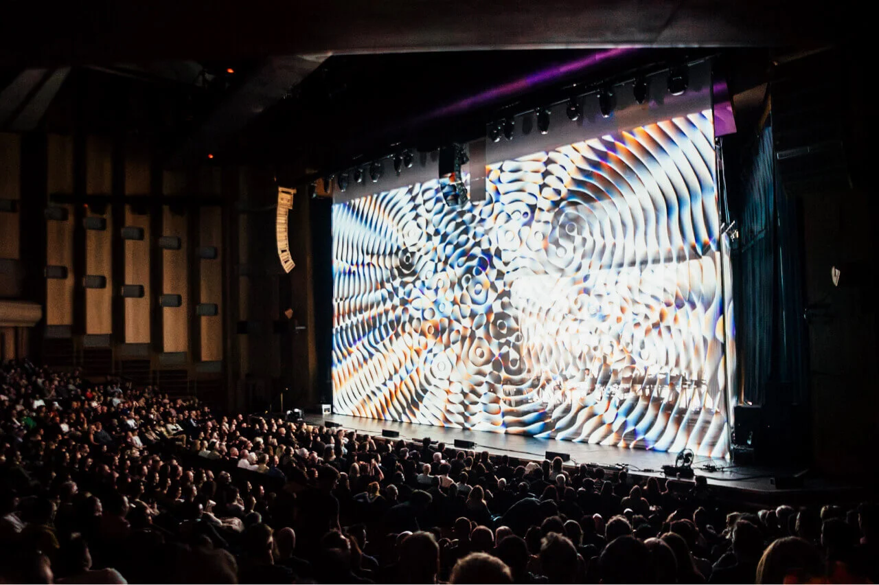 Audience contemplating the 'Cardano Circles' animation during Max Cooper's performance at Barbican Centre Hall in London.