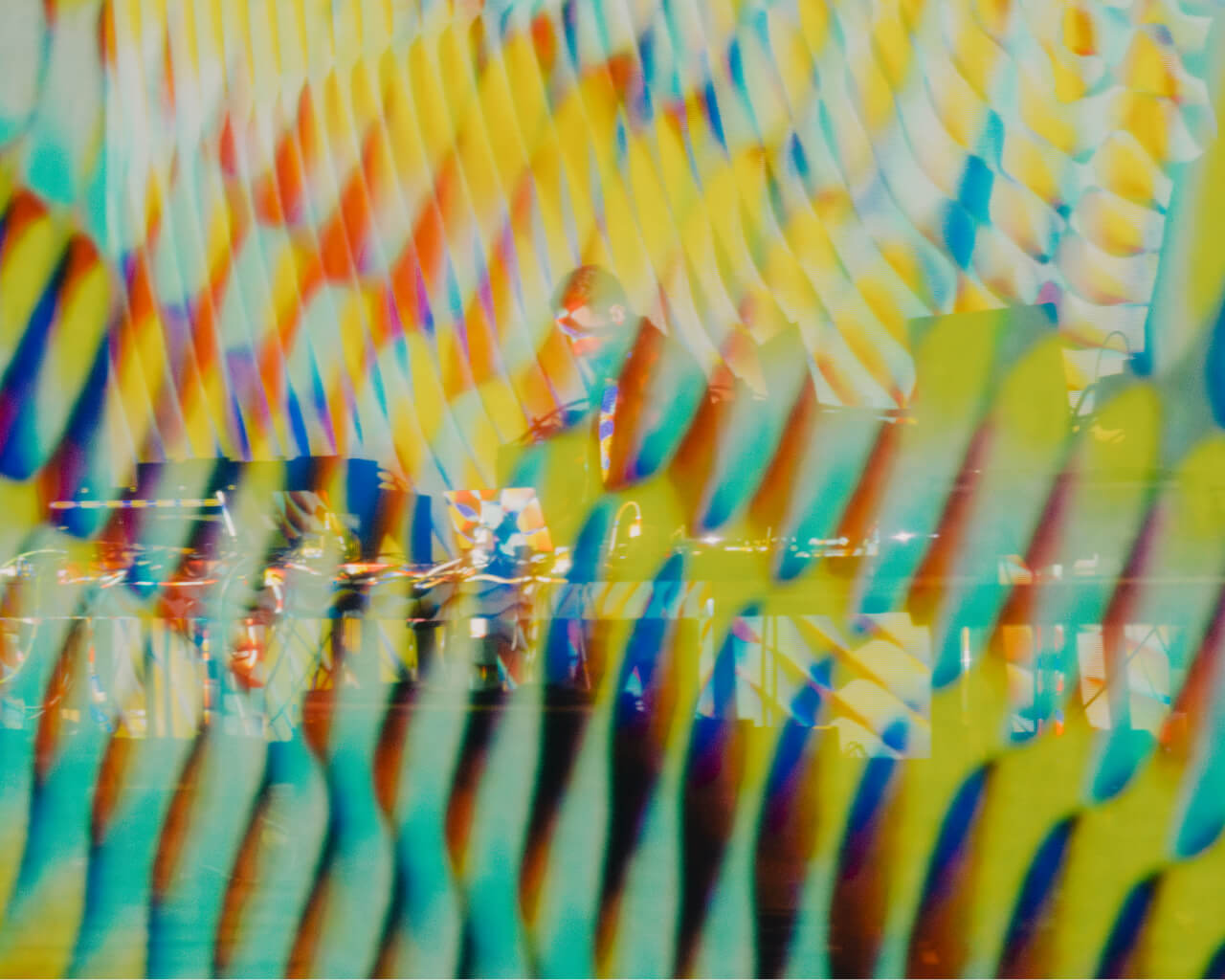 Still from the 'Cardano Circles' animation featuring vibrant yellow, red, and blue colors, with Max Cooper standing in the background performing at Osterfestspiele Salzburg.