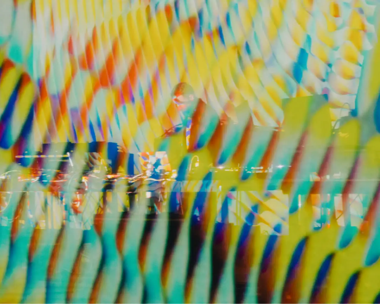 Still from the 'Cardano Circles' animation featuring vibrant yellow, red, and blue colors, with Max Cooper standing in the background performing at Osterfestspiele Salzburg.