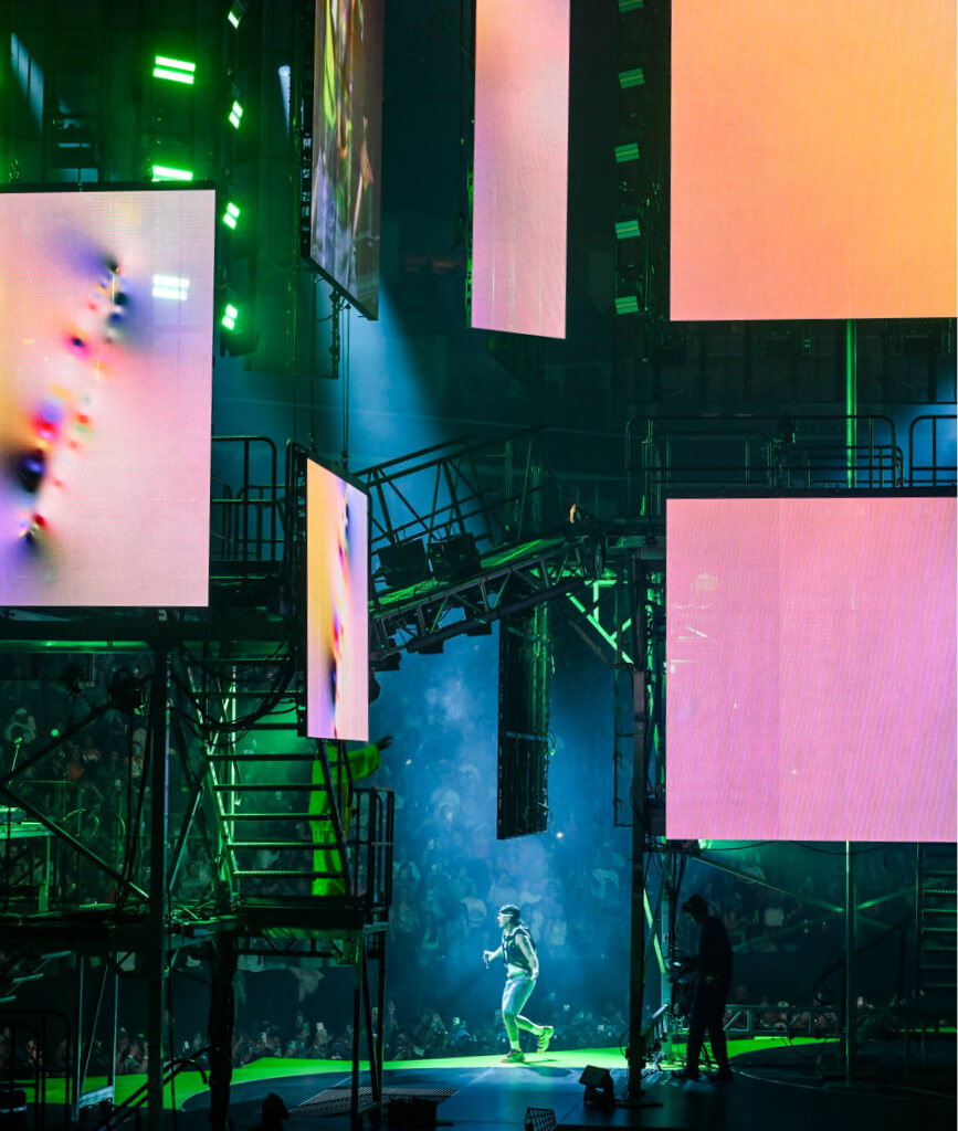 Large LED screens showing artowrks in metal bulding like structures at Ferxxocalipsis Tour concert